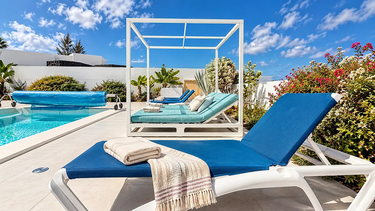 Tumbona azul junto a la piscina y zona de descanso con colchonetas turquesa
