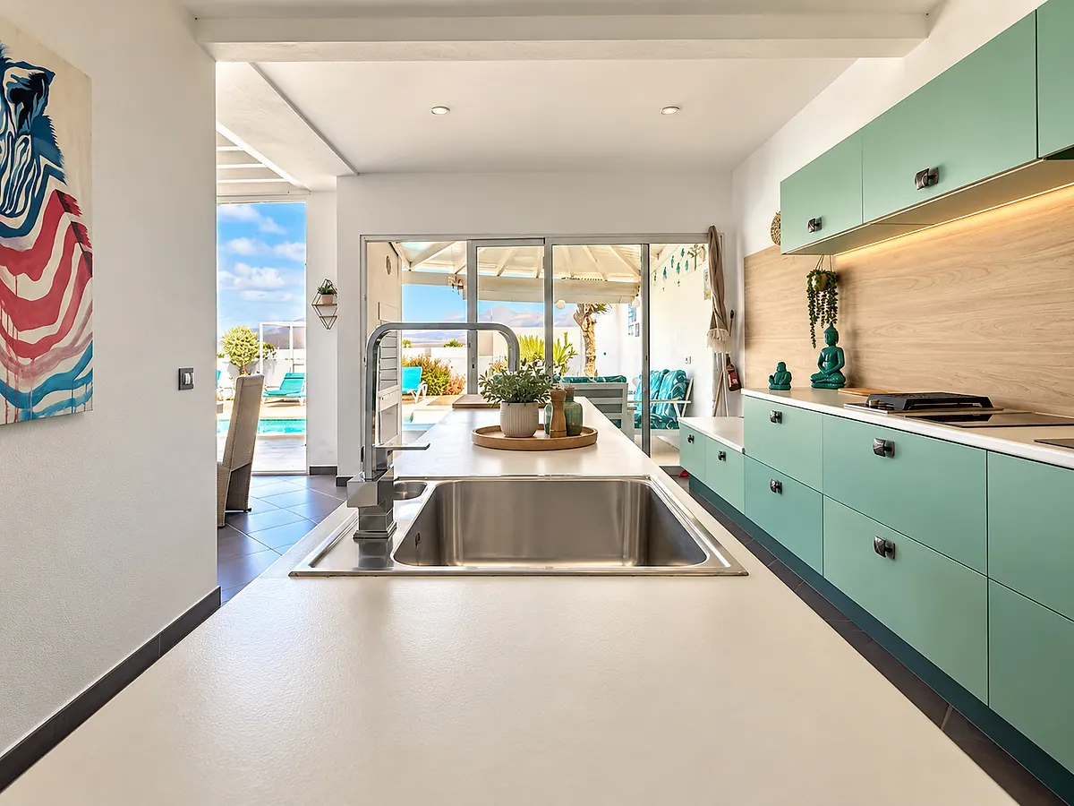 Cocina equipada con placa y fregadero, con la terraza al fondo